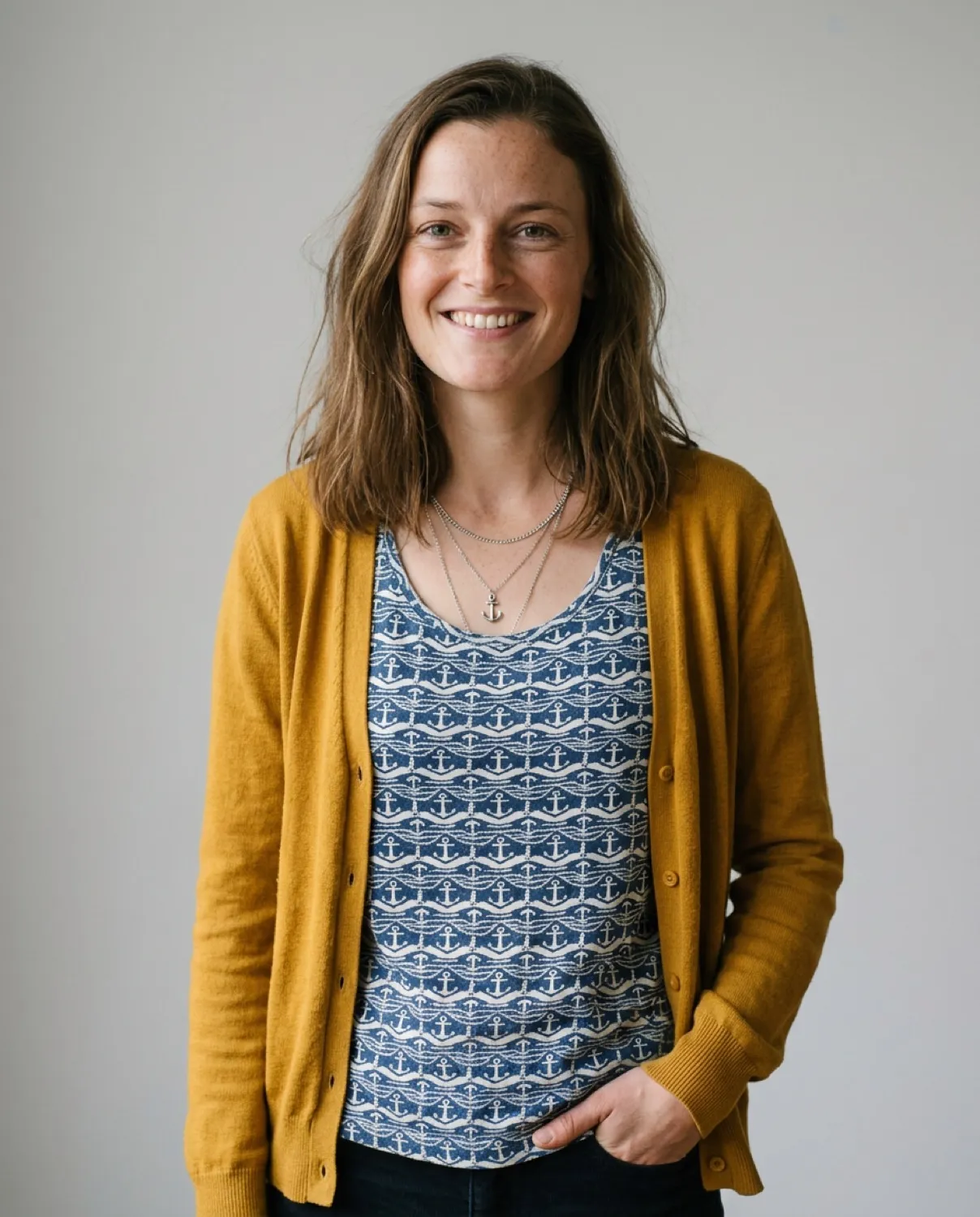 Scarlett smiling in a patterned top and cardigan against a simple backdrop.